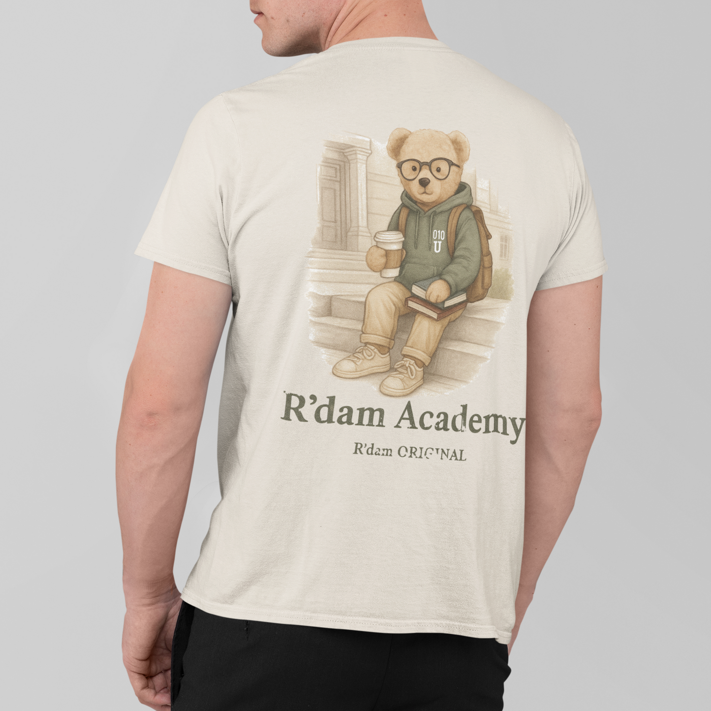 Beige R’dam Academy T-shirt met teddybeer in hoodie, zittend met boeken en koffie"