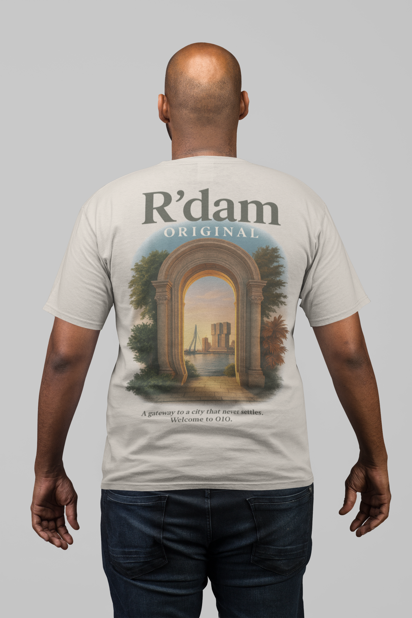 R’dam Original t-shirt met klassieke poort en uitzicht op skyline van Rotterdam bij zonsondergang – unisex in wit en sand.