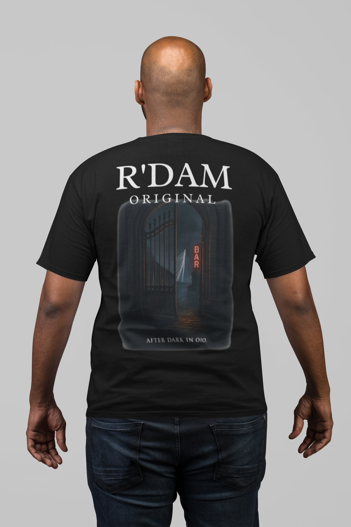 Man draagt zwart ‘Rotterdam Noir’ t-shirt met nachtelijk stadsdesign – limited edition streetwear”
“R’dam Original dark city tee met neon bar en Erasmusbrug in de regen”
“Streetwear shirt geïnspireerd op Rotterdam by night, zwart unisex t-shirt”