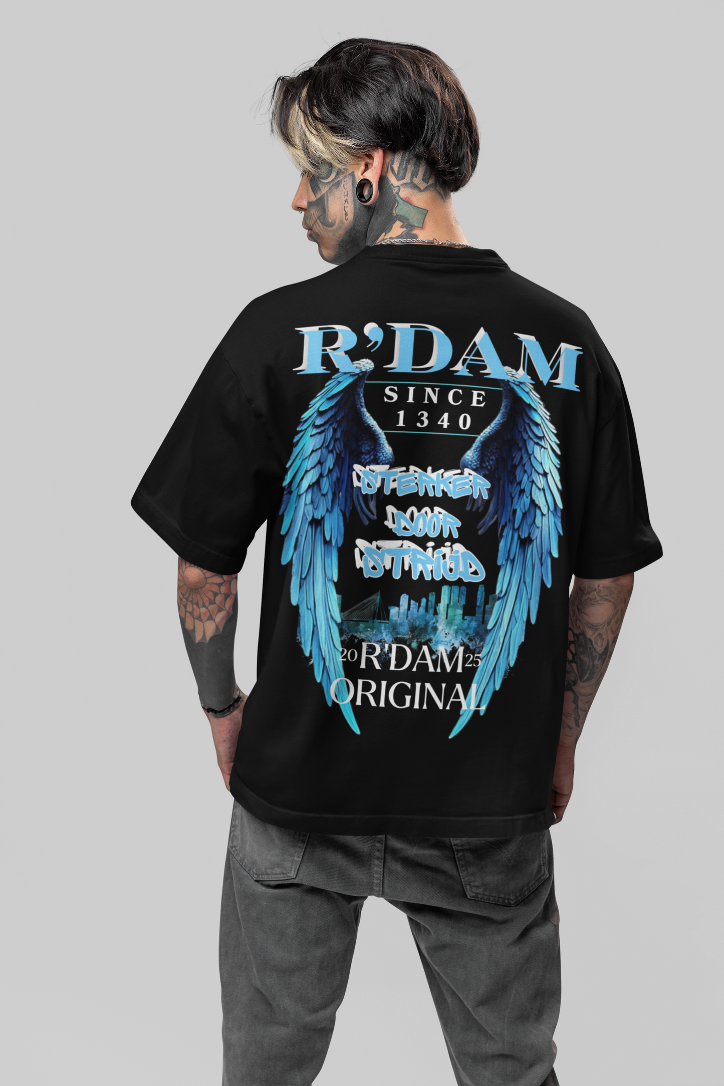 Sterker door Strijd" oversized heren T-shirt van R’dam Original. Heavyweight katoen, urban streetwear met blauwe engelenvleugels en Rotterdam skyline.
